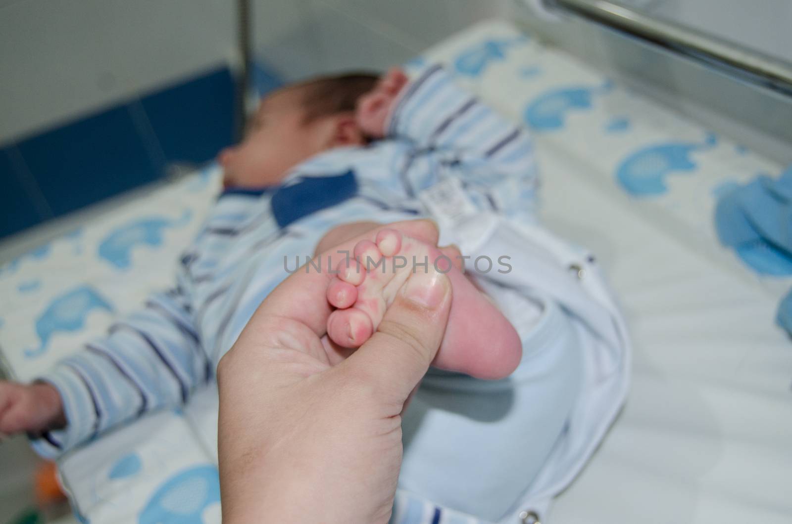 Mother massaging little newborn baby foot, close up