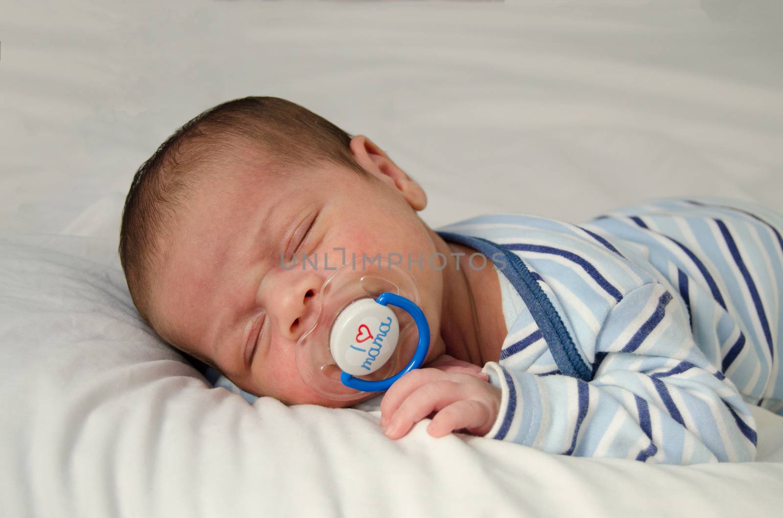 two weeks old newborn baby boy sleeping on white sheet, close up