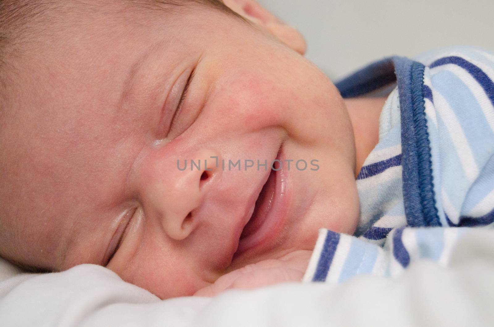 two weeks old newborn baby boy smilleing while sleeping by negmardesign