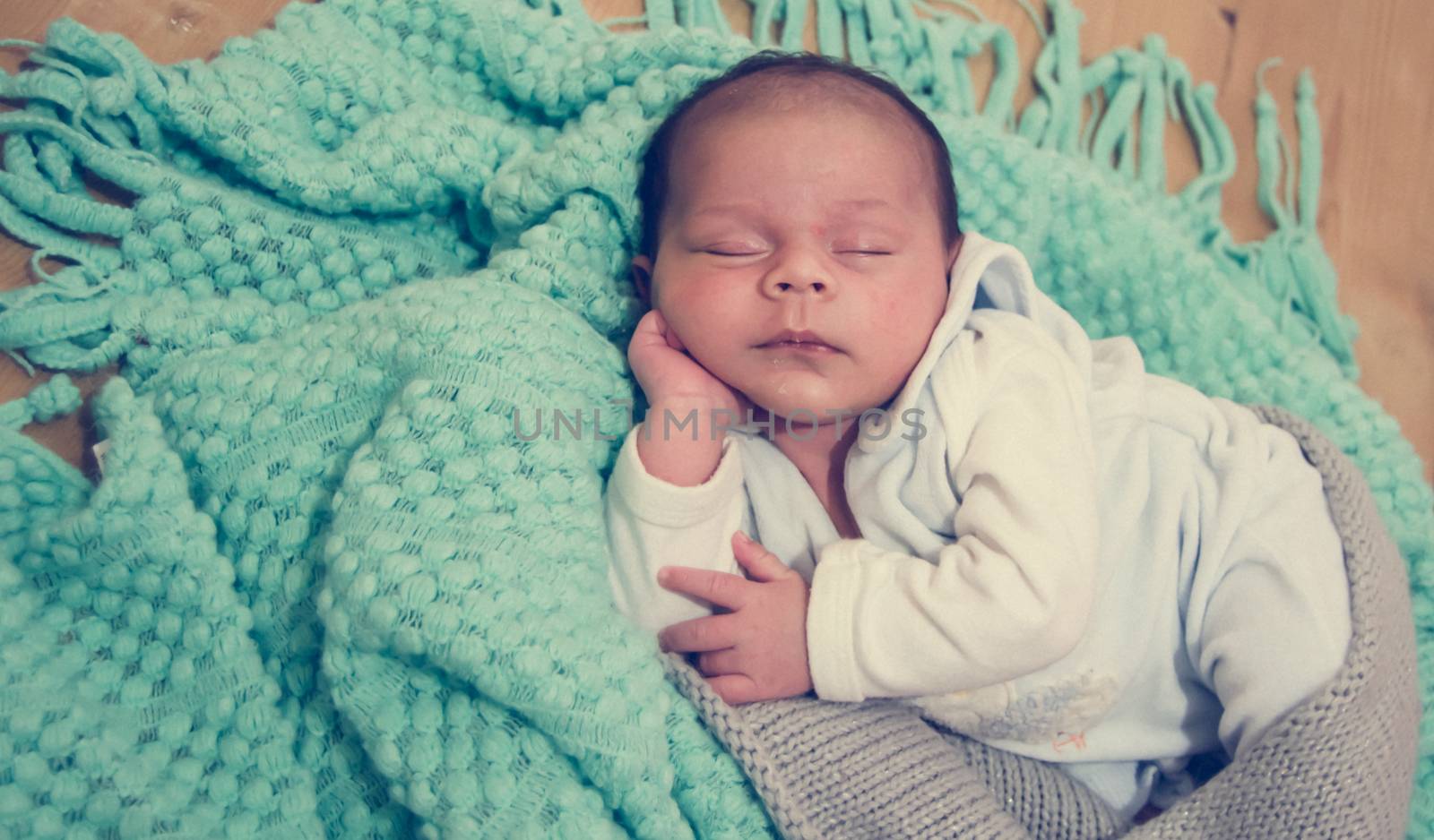 4 weeks old newborn baby boy on green blanket on wooden background by negmardesign