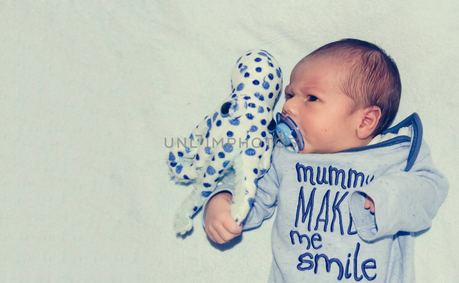 four days old newborn baby boy in the cot with octopus soft toy