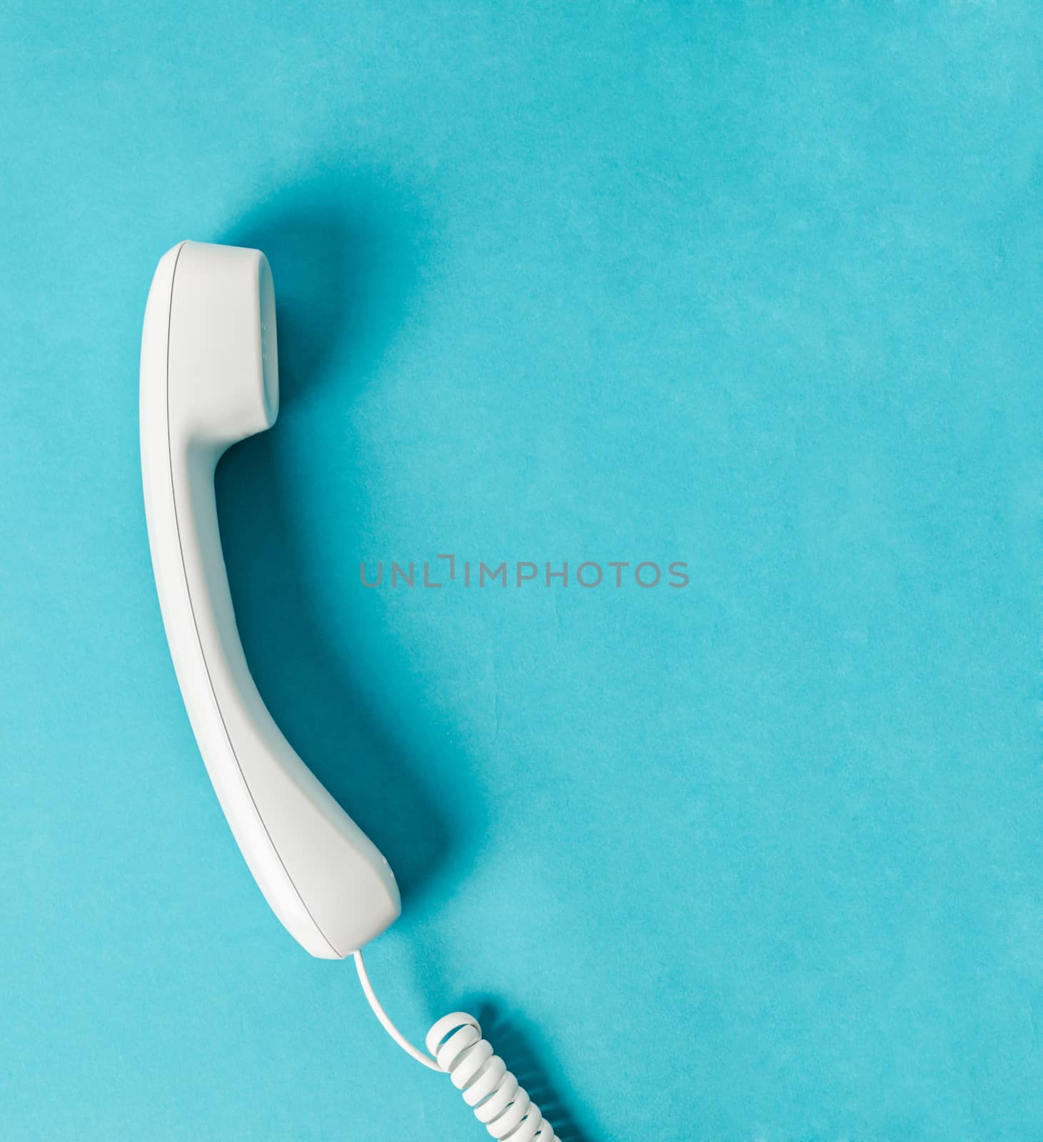 White office desk phone on blue background with free space for your text or message.