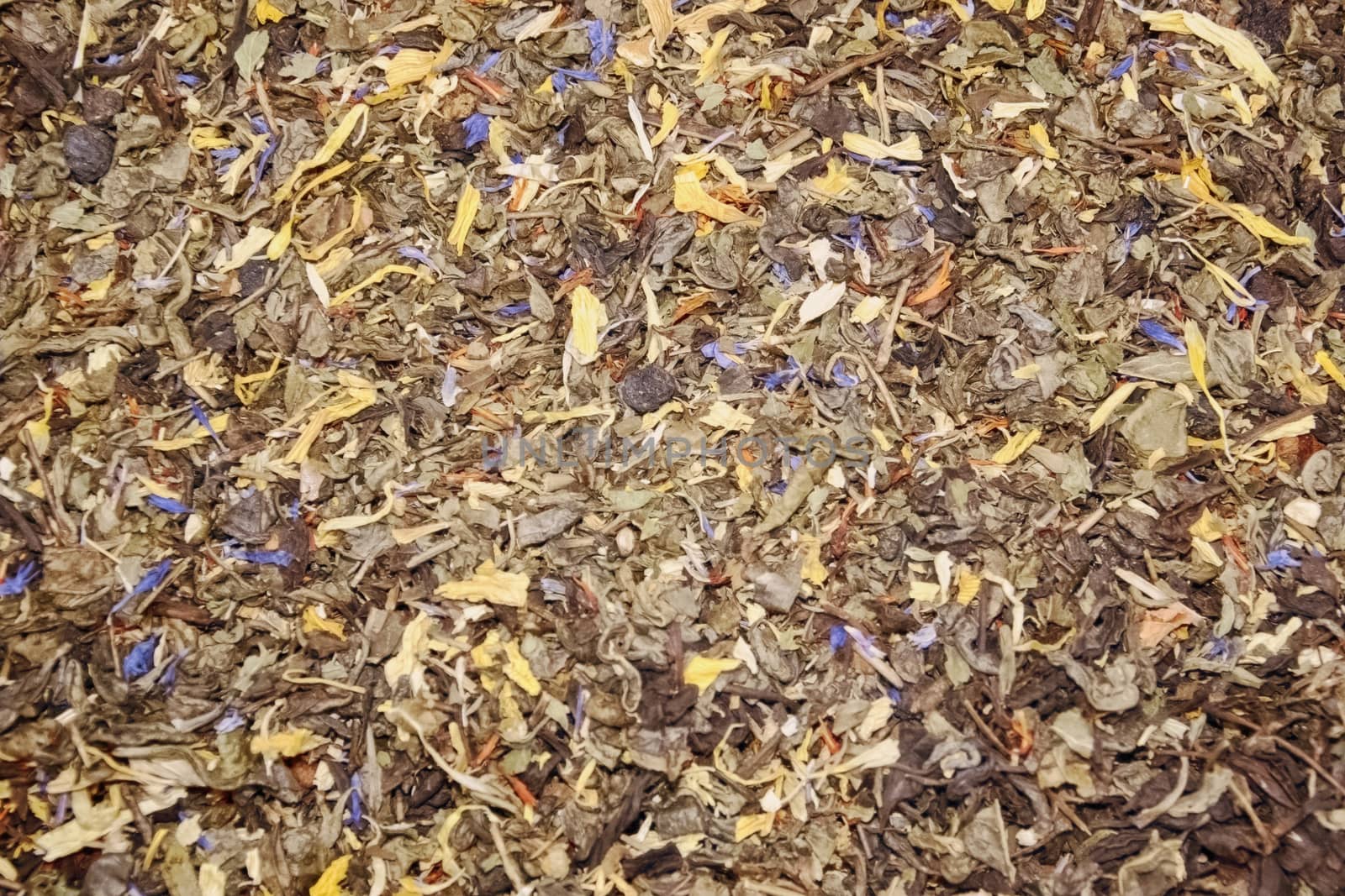 Tea black long leaf with raspberry berries, leaves of blackberry and a blue cornflower on a counter in the market a background tea