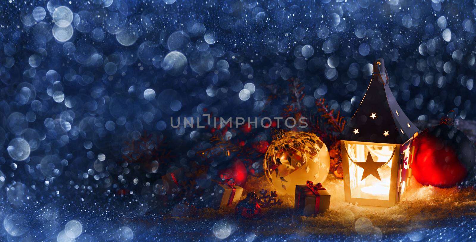 Christmas holidays card with gifts , balls , santa claus hat and glowing lantern in snow in the evening