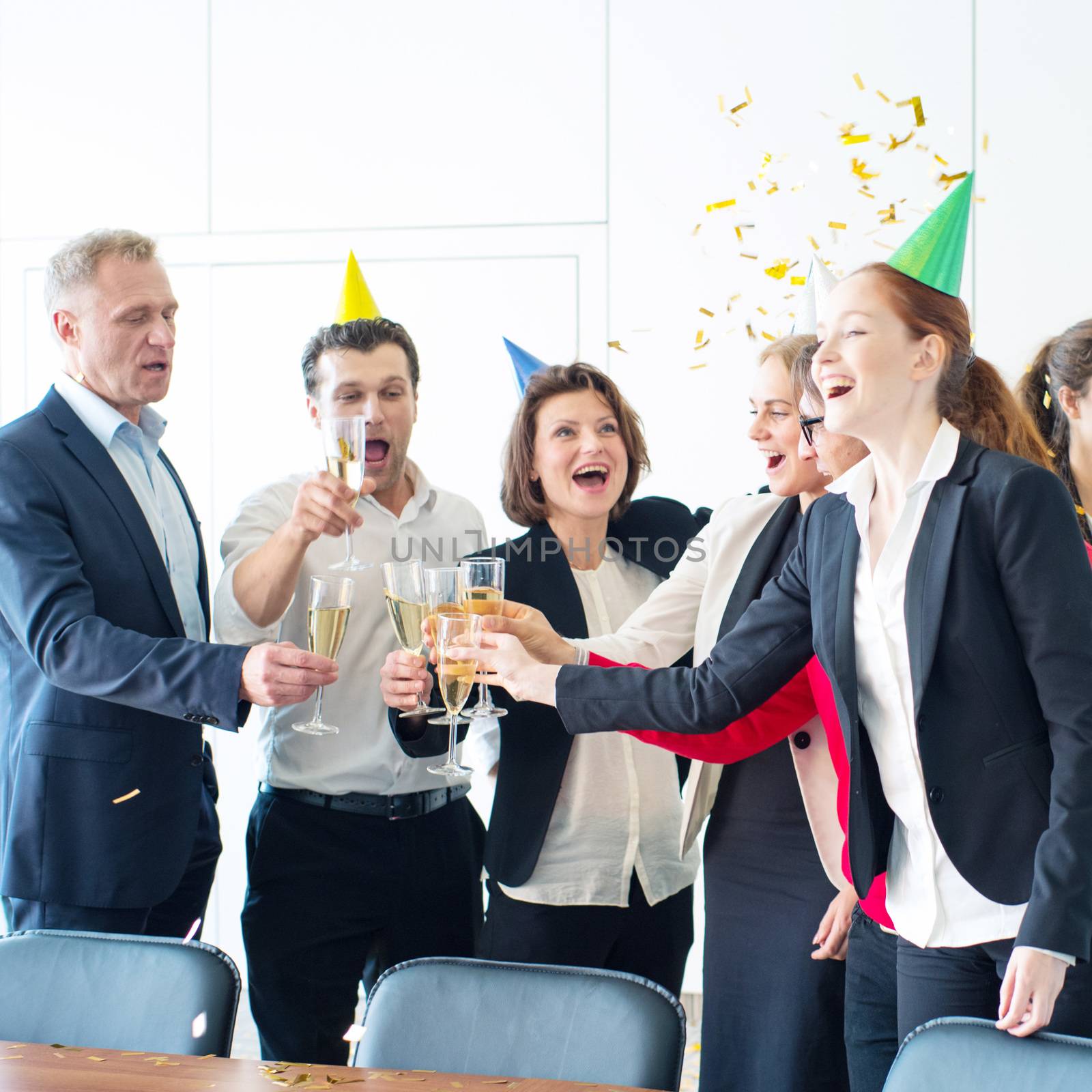 Business people celebrating victory at office party holding glasses of champagne