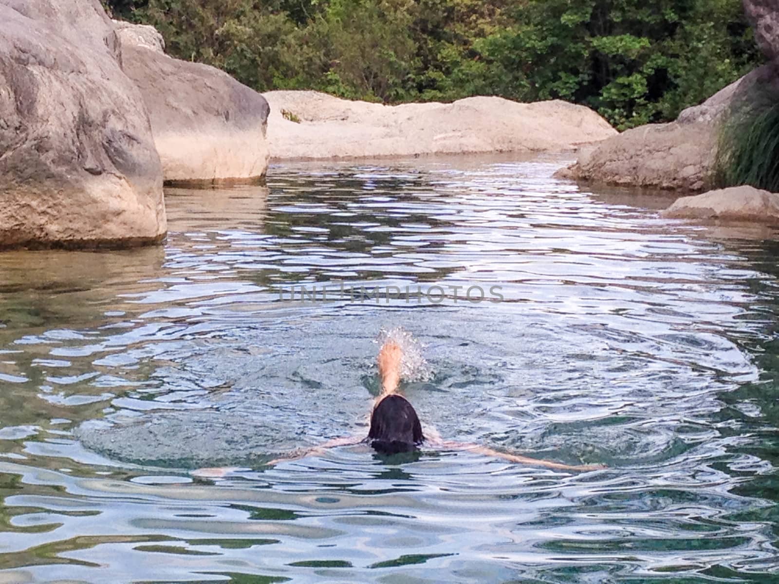 Woman swimming in a natural creek swimming pool