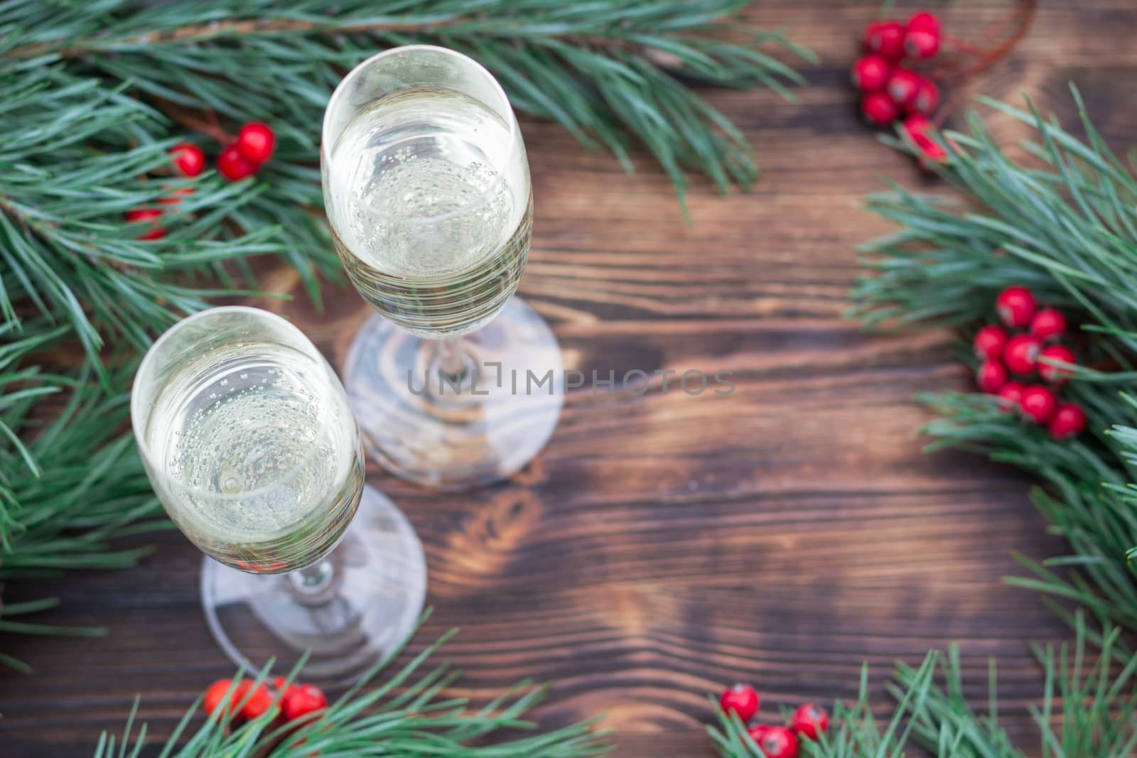 Christmas and New Year seasonal composition with pine tree branches, two glasses of champaign and red rowan berries