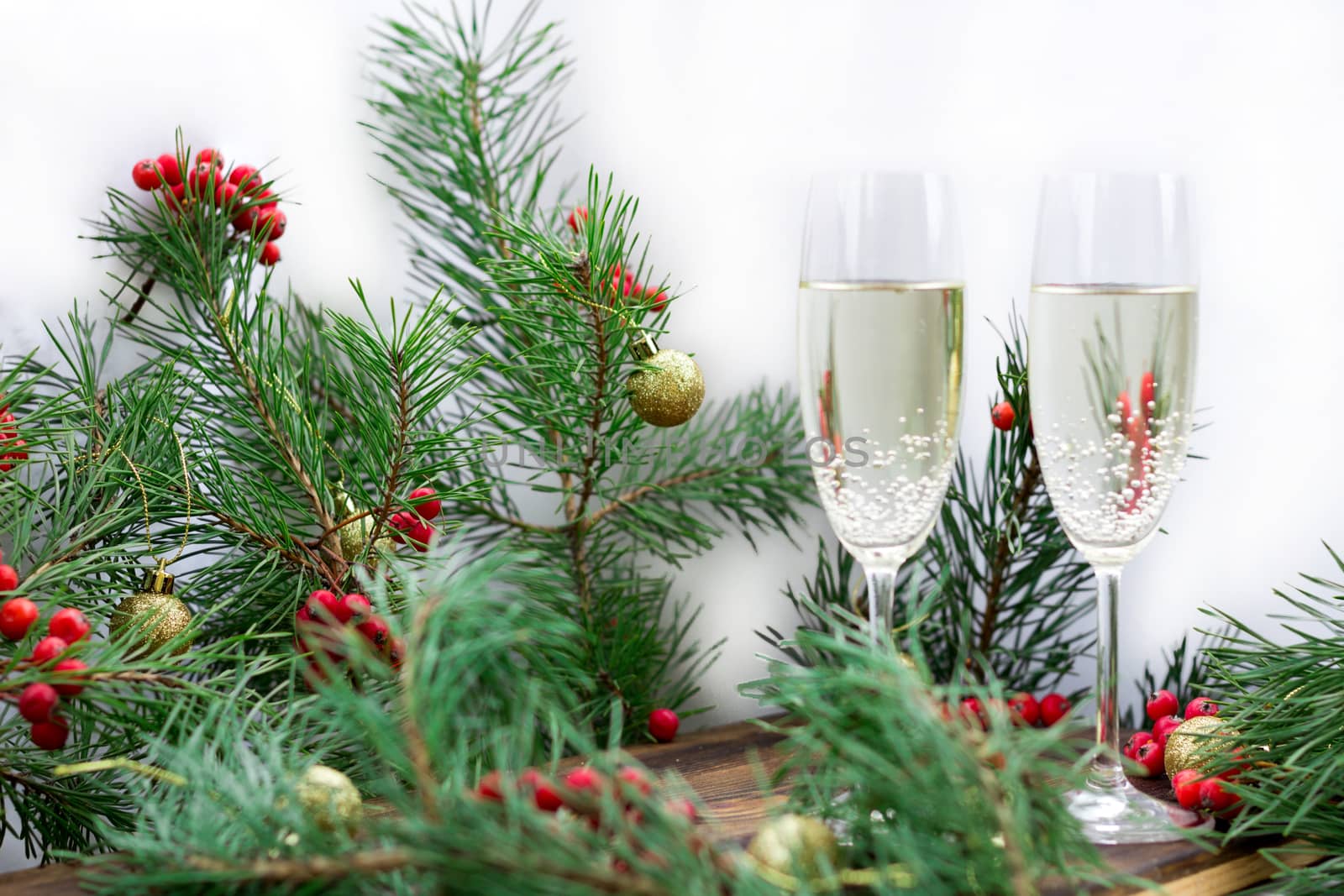 Christmas and New Year seasonal composition with pine tree branches, two glasses of champaign, golden balls ornament and red rowan berries