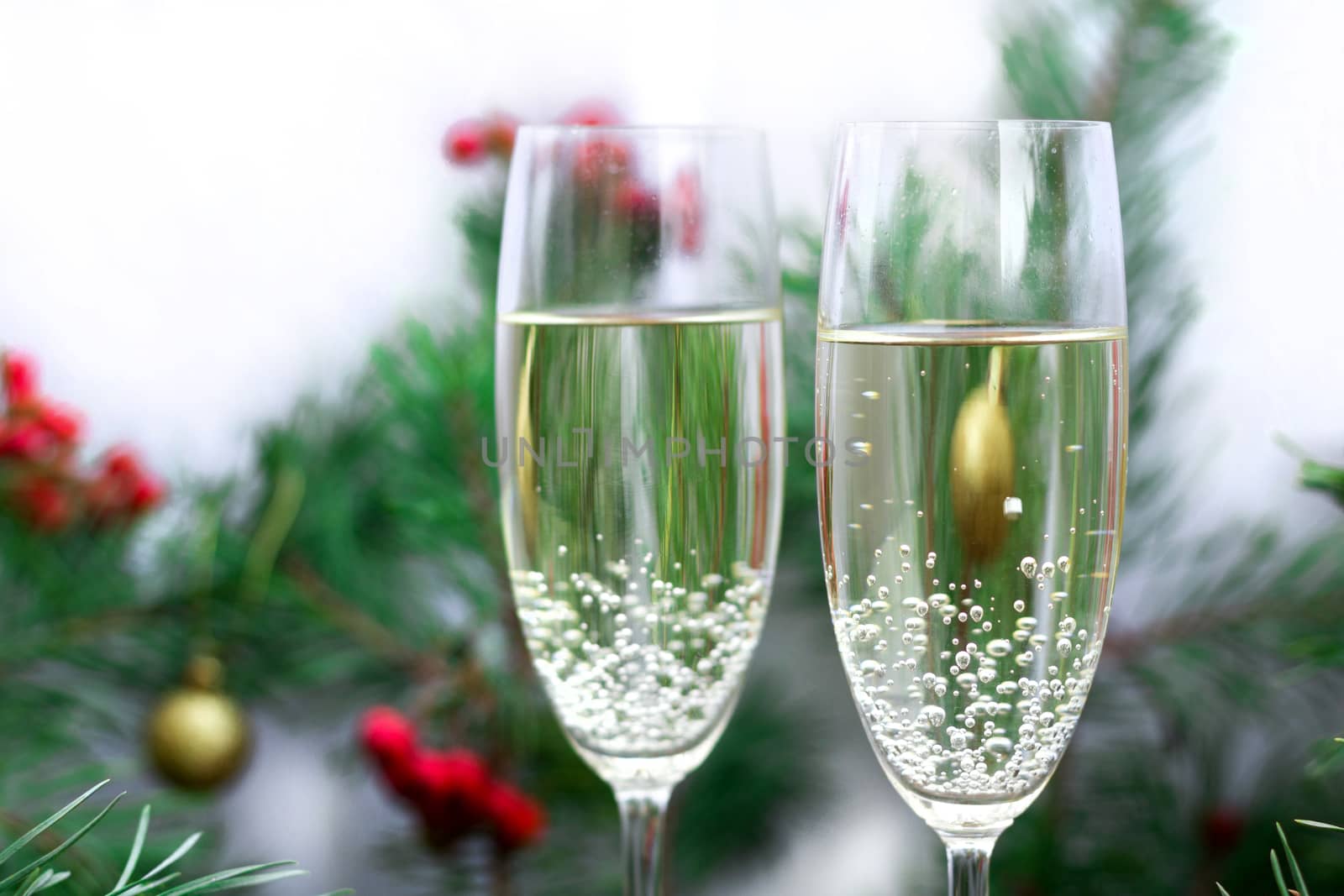 Christmas and New Year seasonal composition with pine tree branches, two glasses of champaign, golden balls ornament and red rowan berries