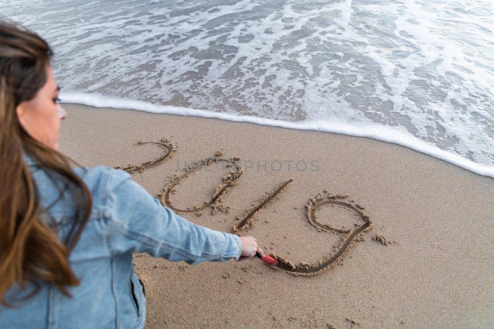 Girl writing 2019 on the sand while enjoying the sea