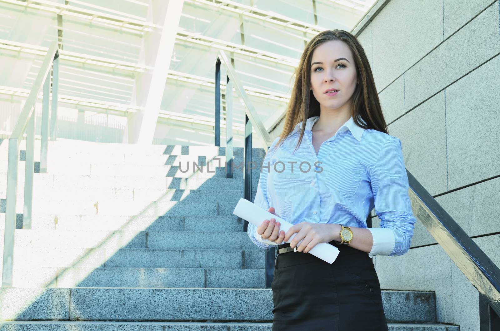 Business woman standing on the background of a tall building with a drawing project in hand