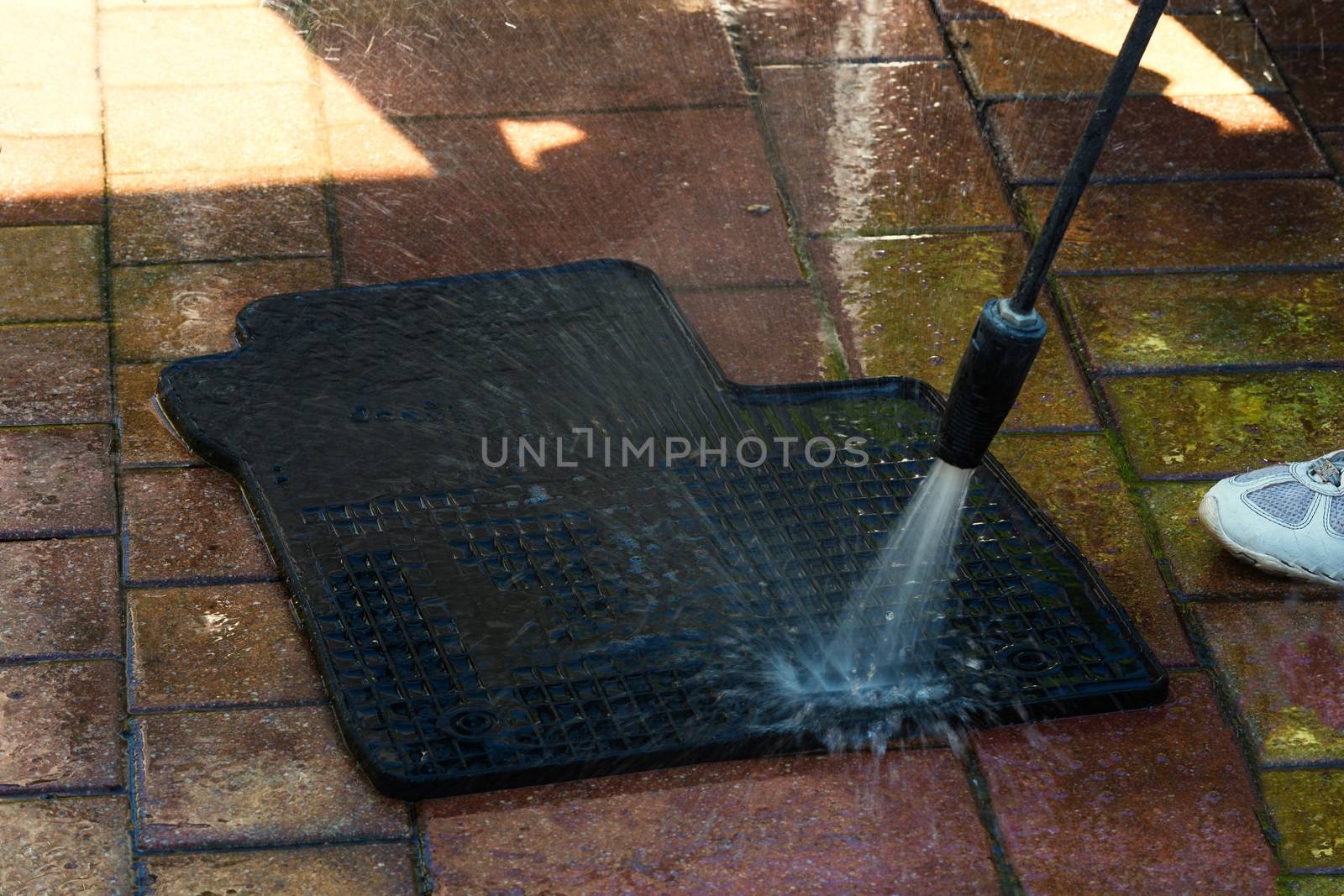 Close up cleaning of car mat with a pressure washer