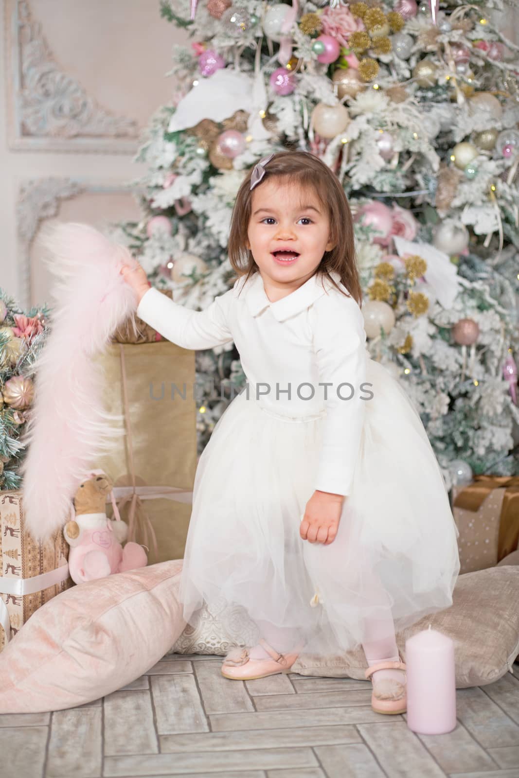 Merry Christmas and Happy Holidays ! Cute funny little child girl near decorated Christmas tree indoors