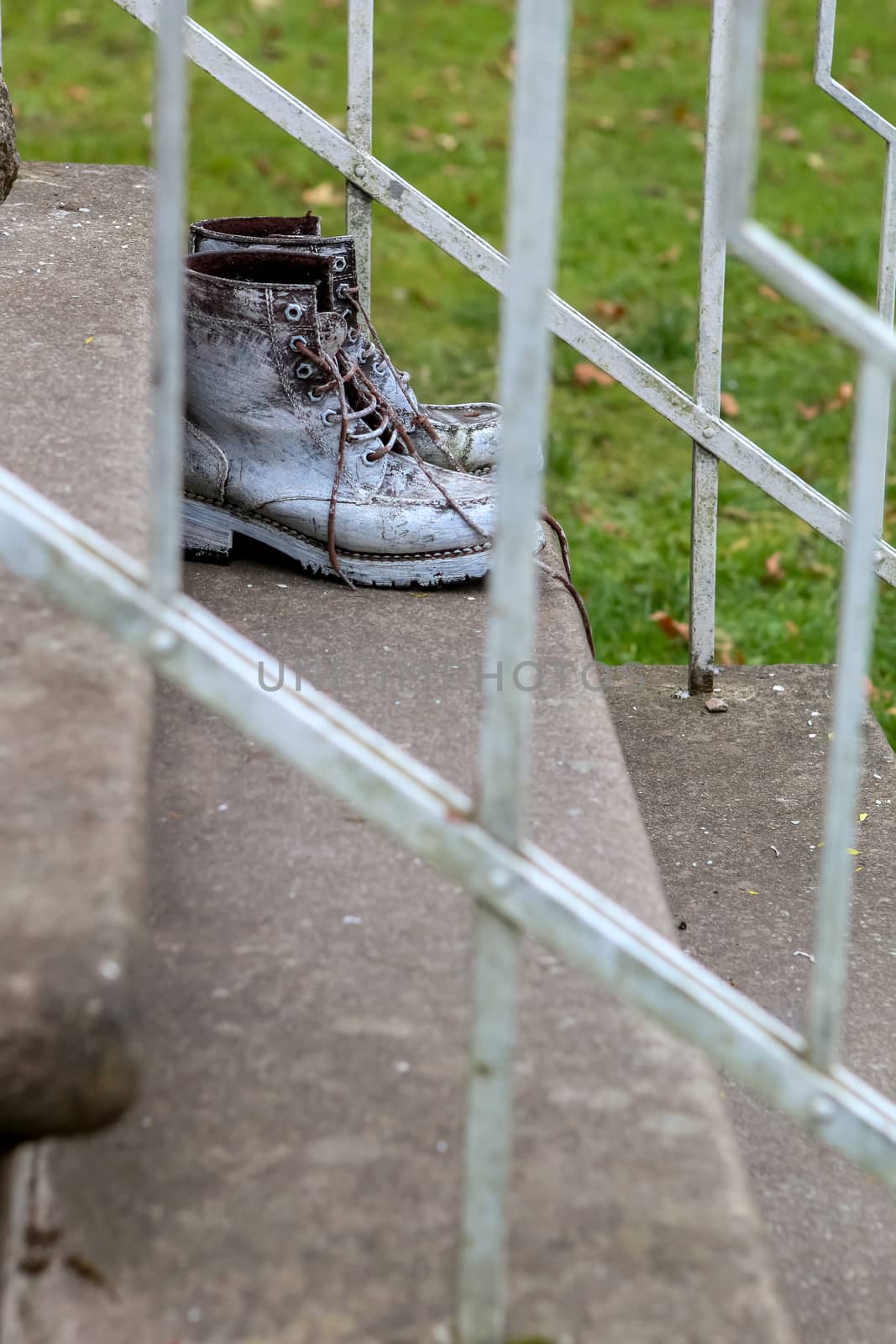 Old brown work boots. Boots smeared with white paint. Dirty boots on the stairs. Dirty old workboots on stairs.