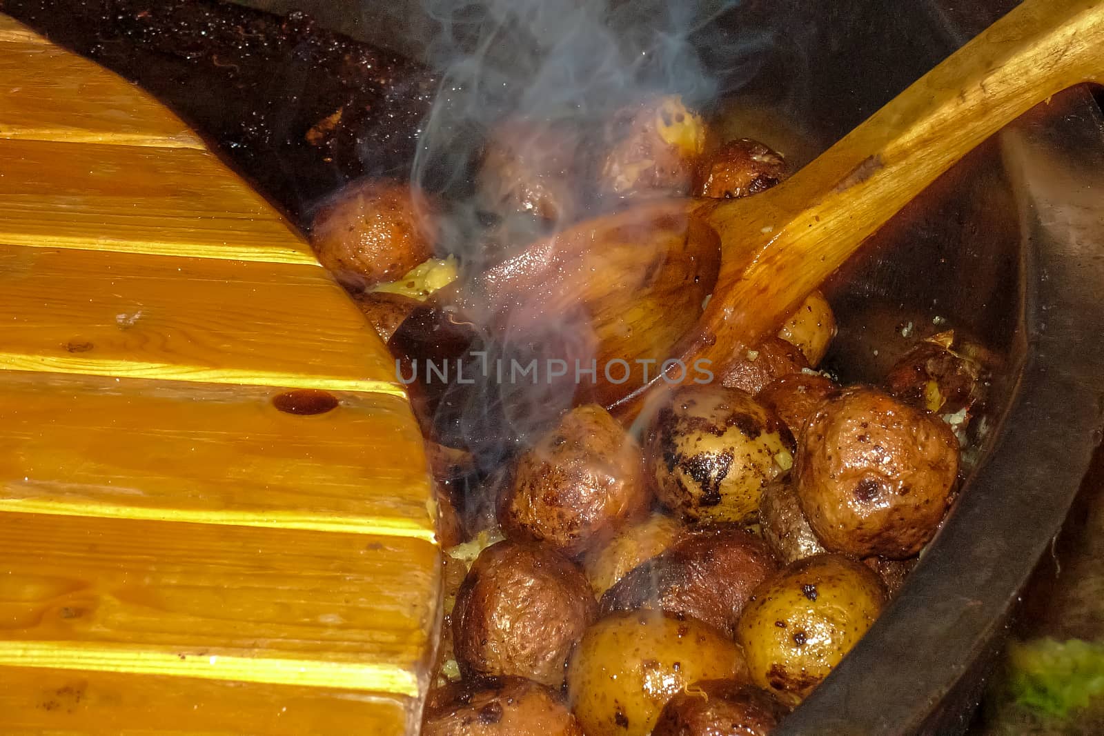Fried potatoes with the peel. Potatoes fried in a pan on the bonfire. Potatoes with peel in pan in outdoor