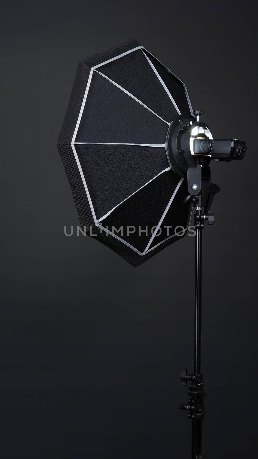 Professional photo studio soft box and flash on the tripod for stillphoto or video production which ready for shape the light for softer, harder or sharper by crew team before shooting on black background.