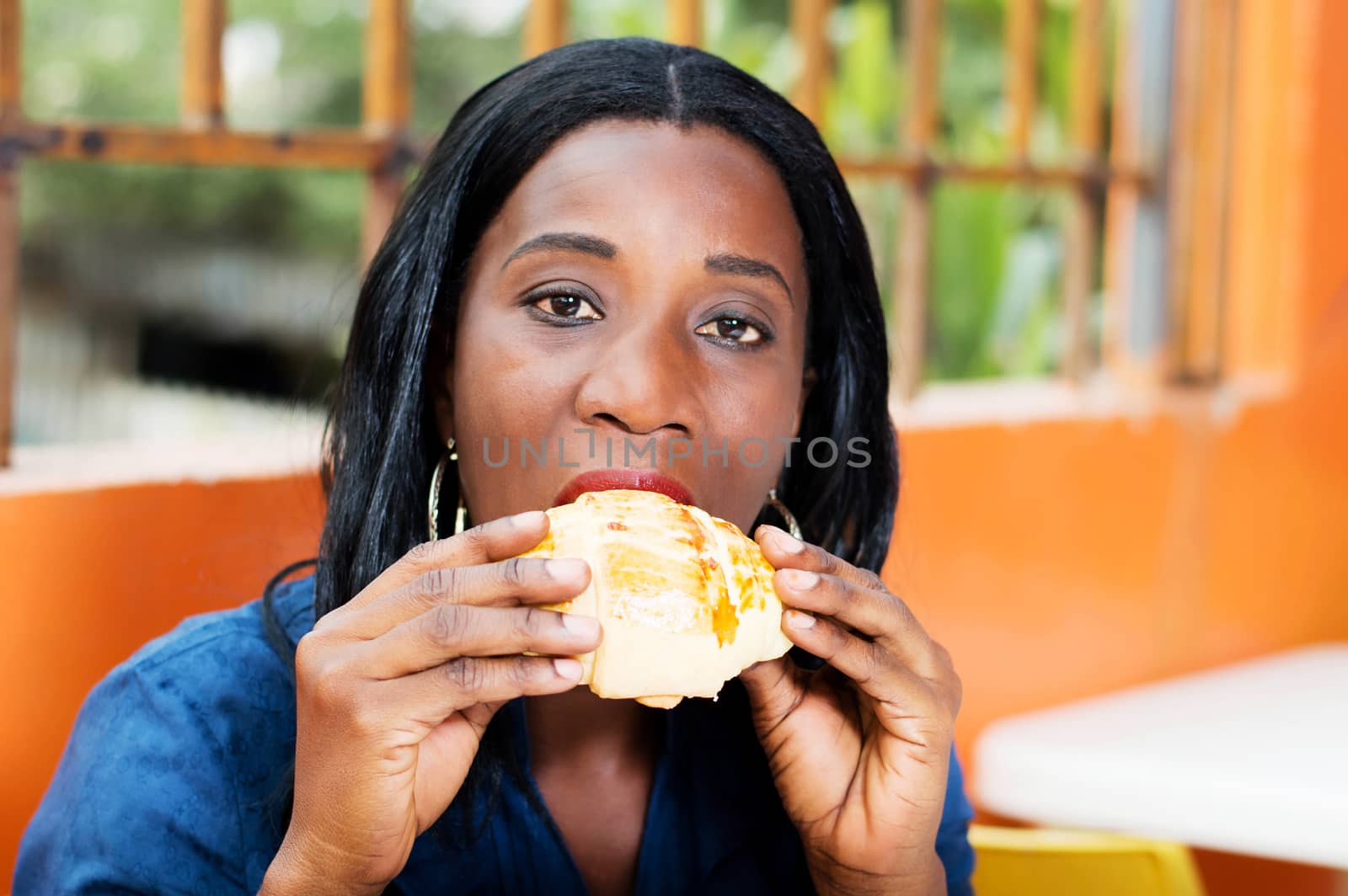 young woman is eating a bread she held in her hands.