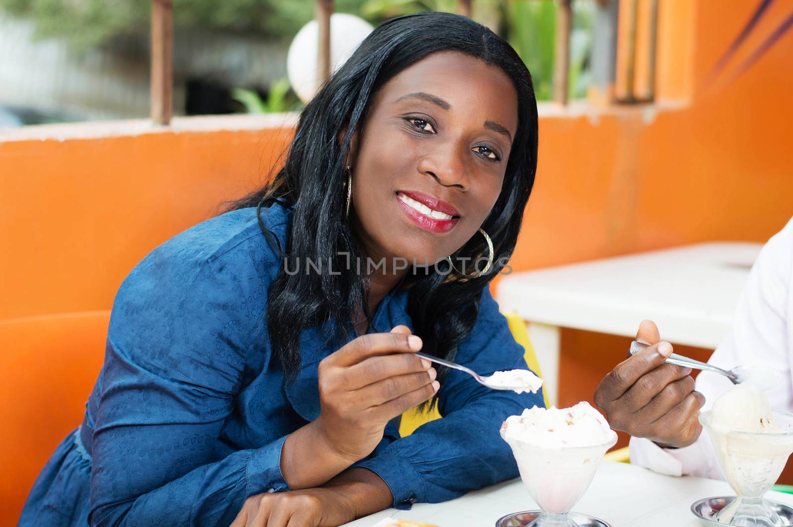 smiling young woman sitting at the restaurant takes her breakfast.