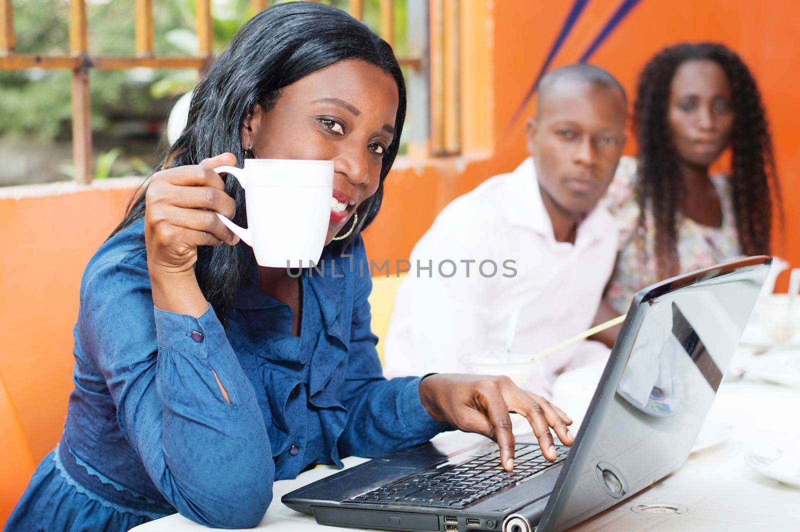 This beautiful smiling businesswoman, working on her laptop with a cup of coffee in hand.