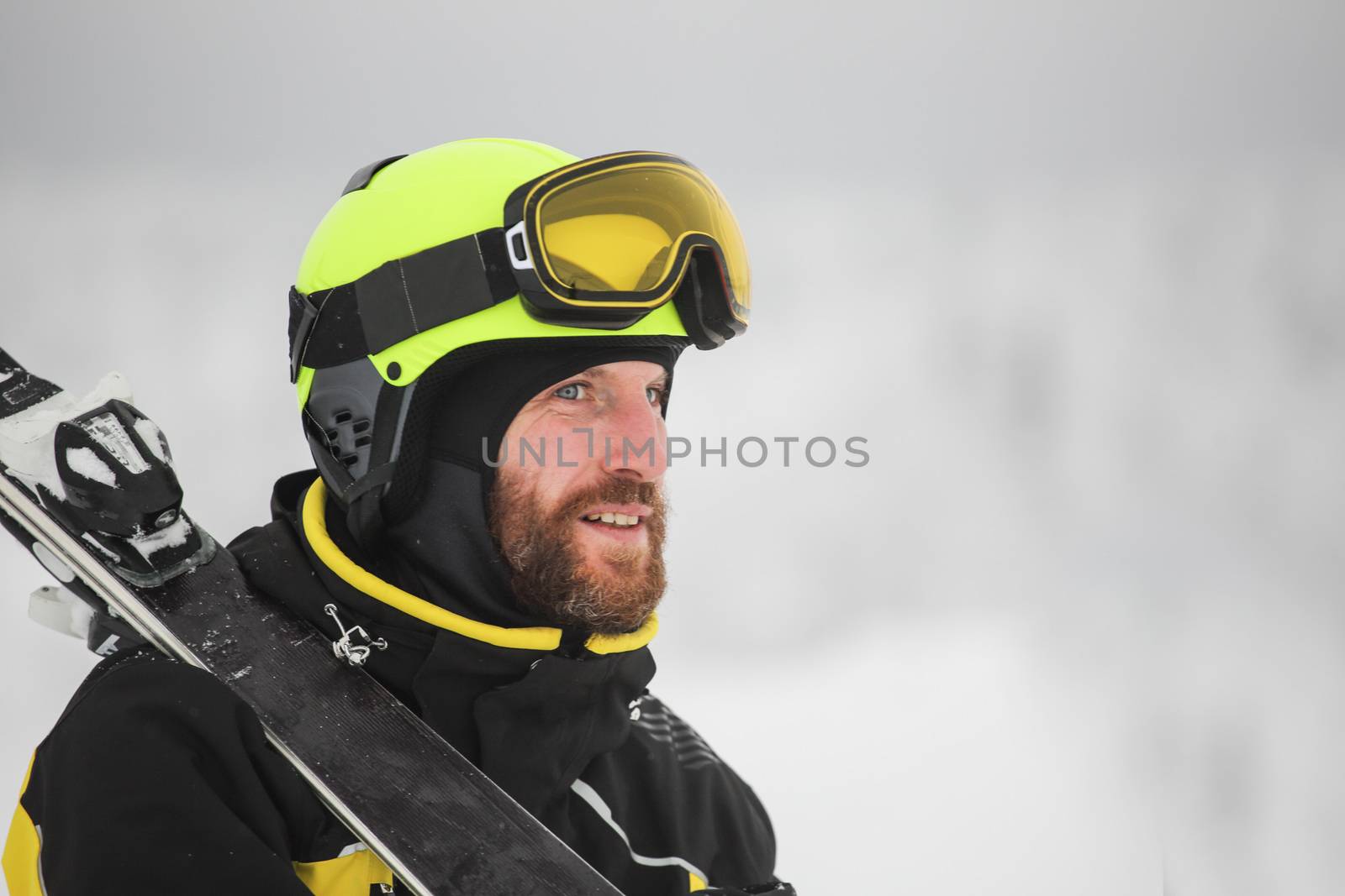 Portrait of a happy male skier in the alps with ski on shoulder