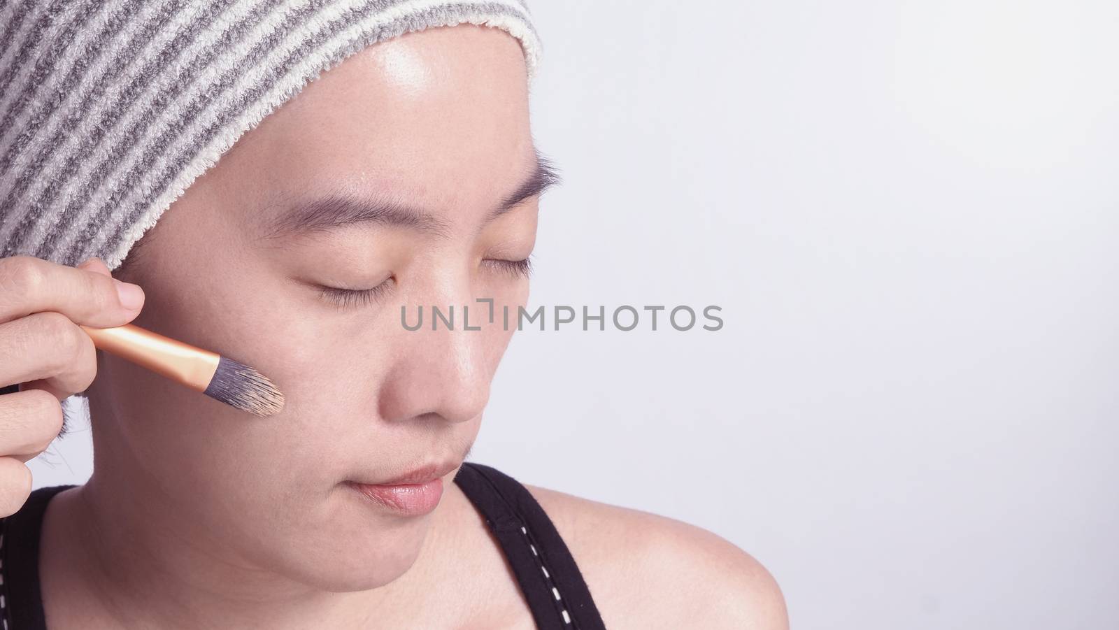 Asian girl or woman 40 years old beautiful face with japanese look making up by foundation liquid and cosmetic brush on sensitive skin for helping her complexion look flawless and real no retouch