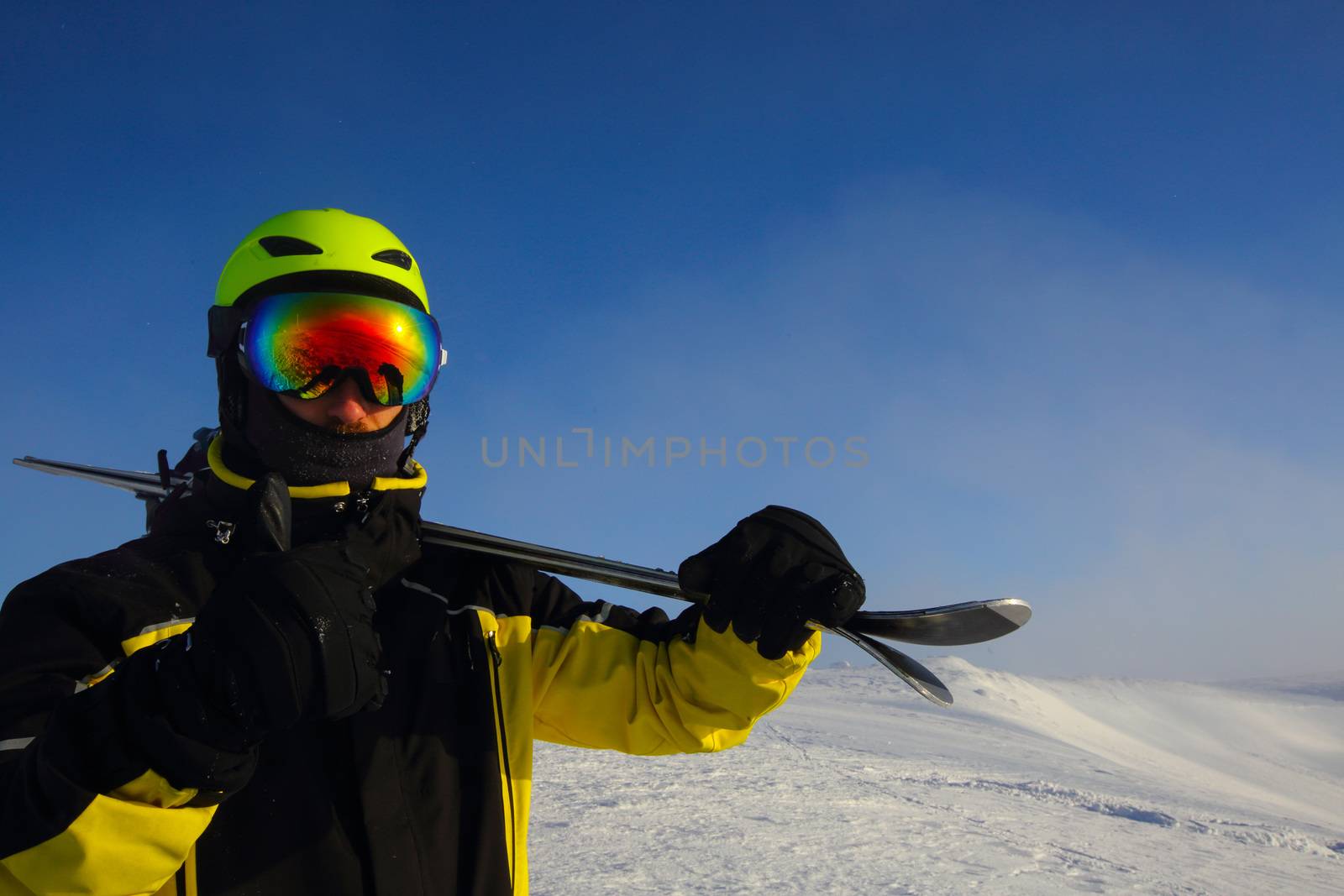 skier holding a pair of skis looking at the mountains