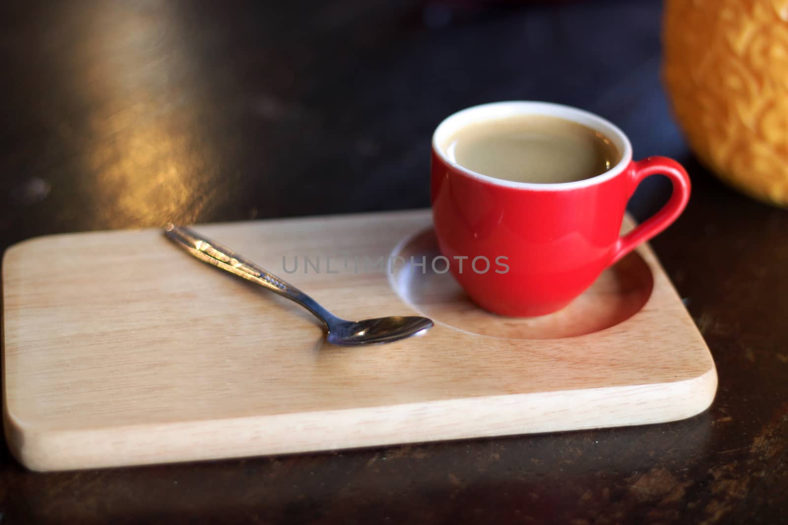Red cup of coffee on wooden tray.
