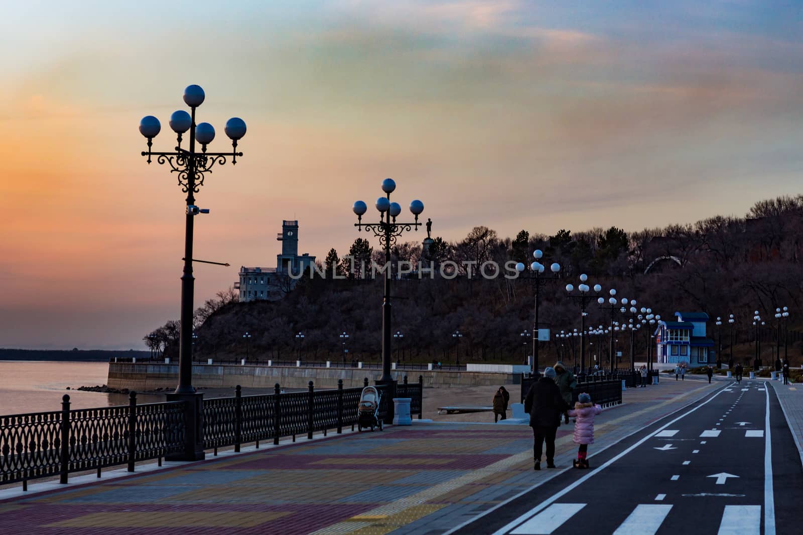 Sunset on the embankment of the Amur river in Khabarovsk. The sun set over the horizon. The embankment is lit by lanterns.