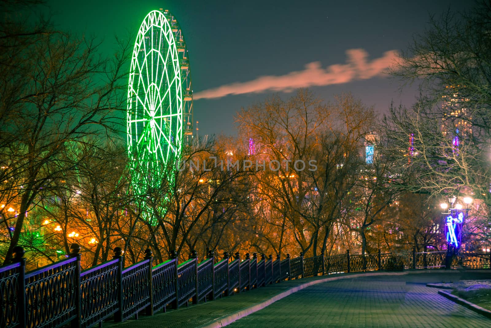 Ferris wheel on the banks of the Amur river in Khabarovsk against the night sky. A bright illumination. Photographed at long exposure.