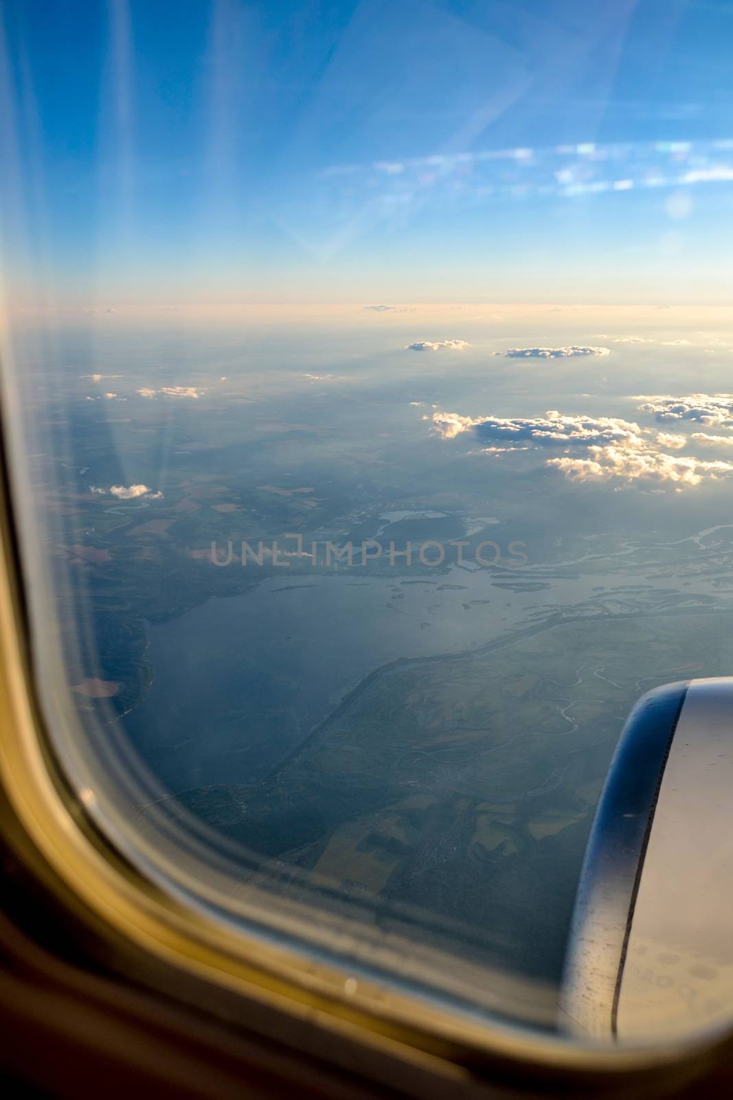 Sky from a plain. View through the window of an aircraft. The sunset colors. Above clouds