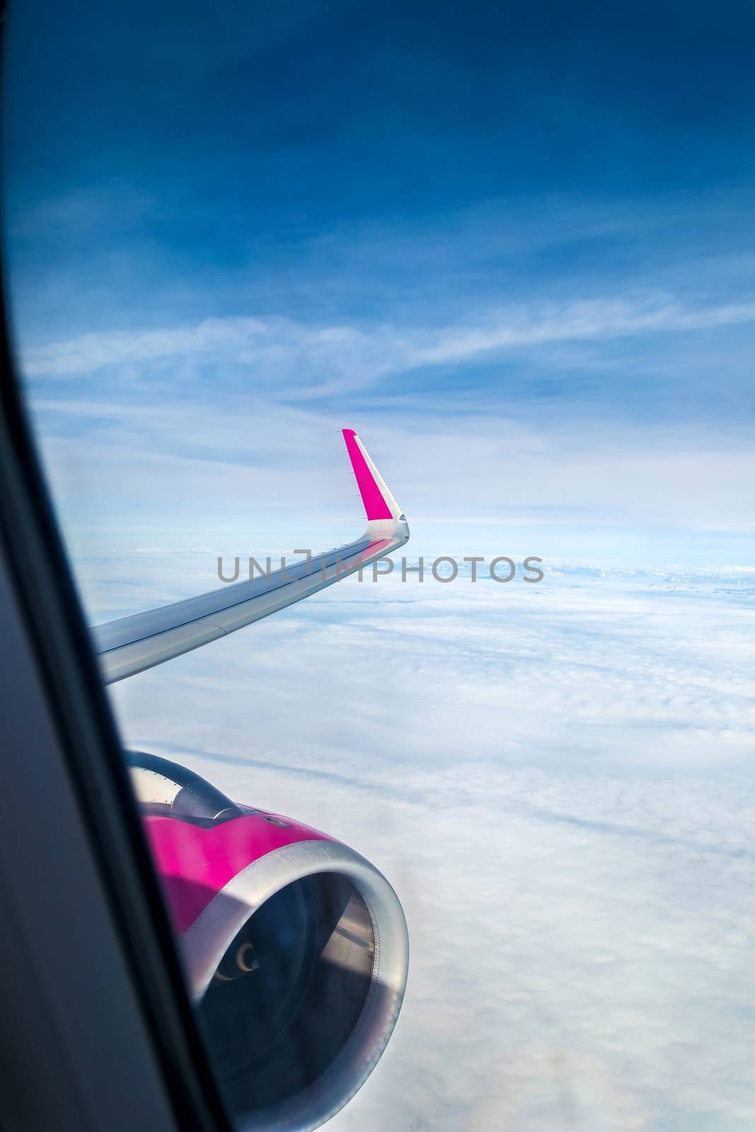 Sky from a plain. View through the window of an aircraft. Wing of the plane above clouds.