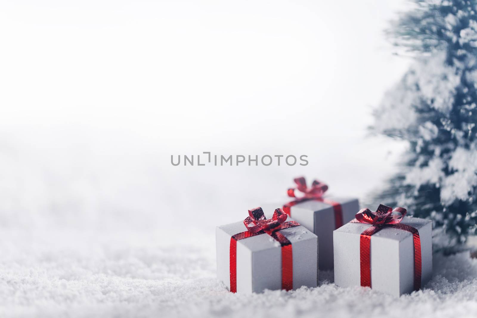 Decorated christmas gifts under fir tree on snow , background with copy space