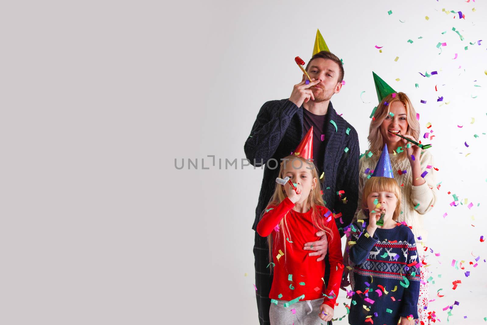 Family blowing party trumpets with confetti celebrating new year