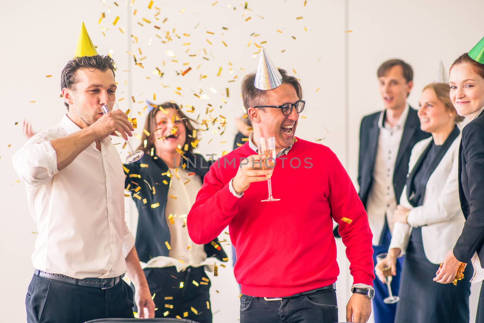 Business people celebrating victory at office party holding glasses of champagne