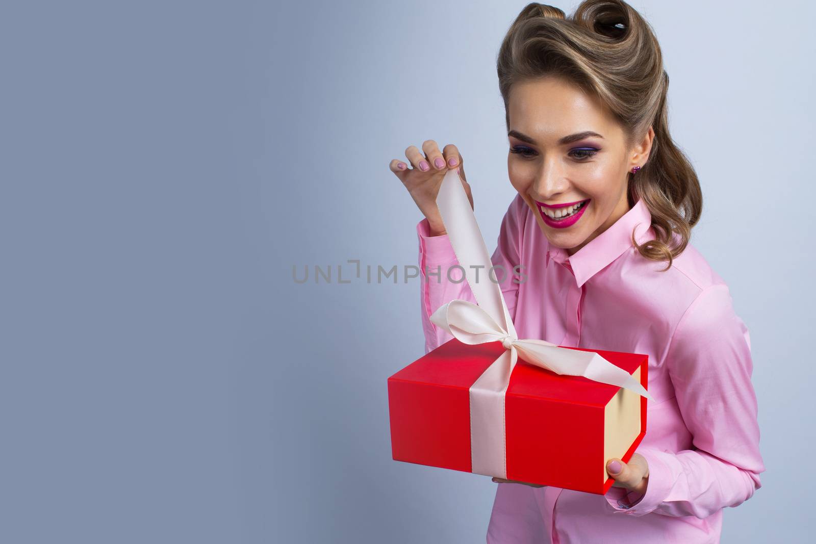 Happy beautiful funny woman unwrapping gift box