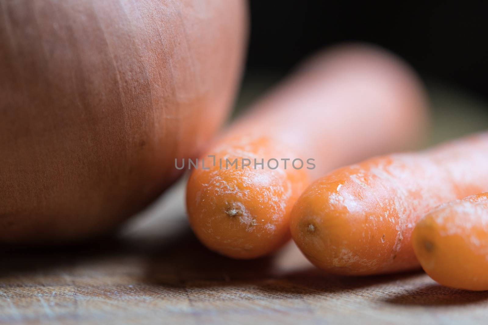 Closeup of a onion and three orange carrots on a table