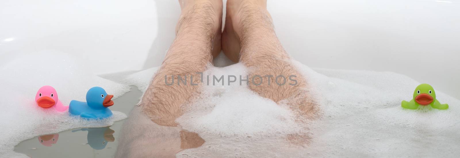 Men's feet in a bright white bathtub, selective focus on toes