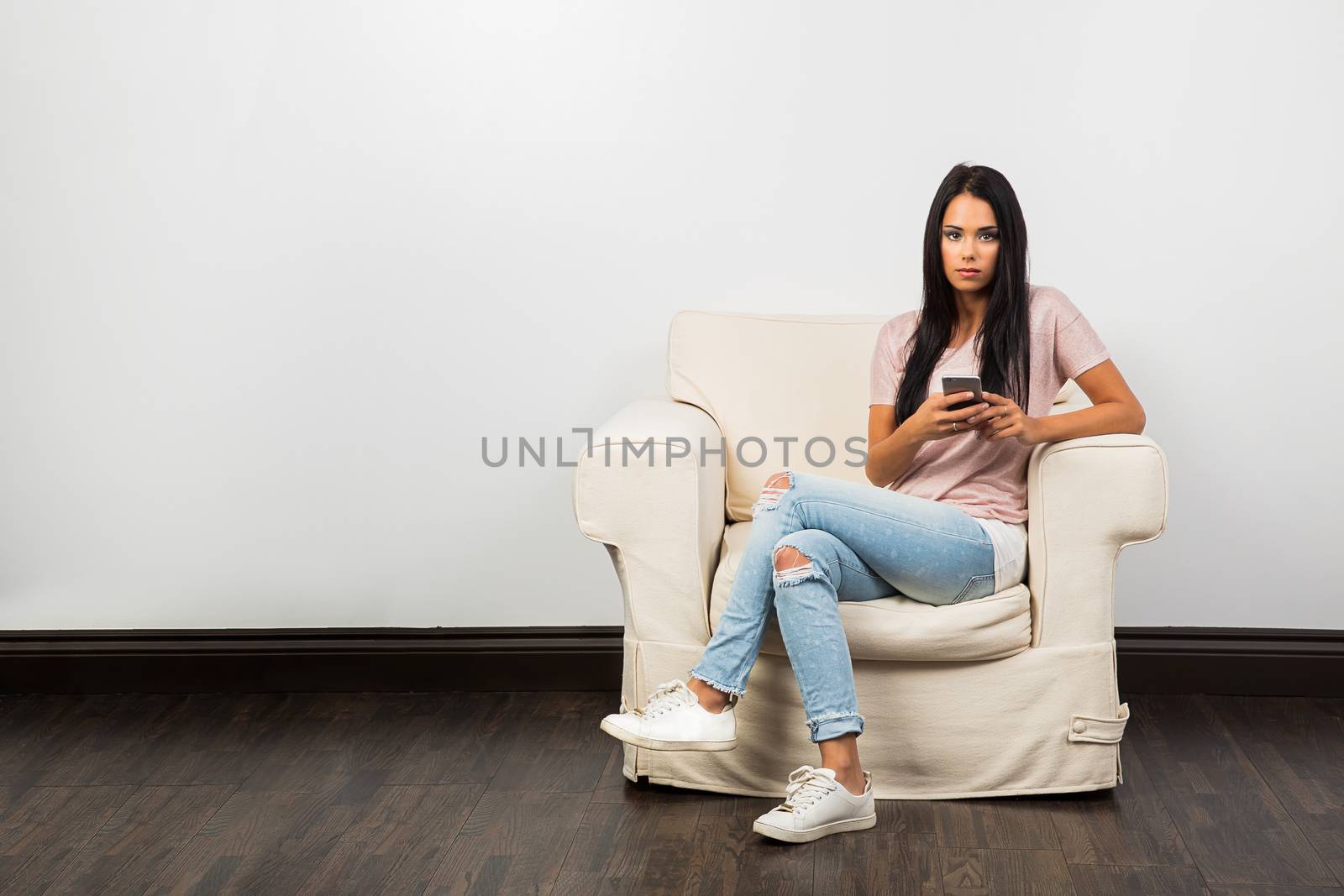 twenty something woman sitting on a coach holding a smart phone