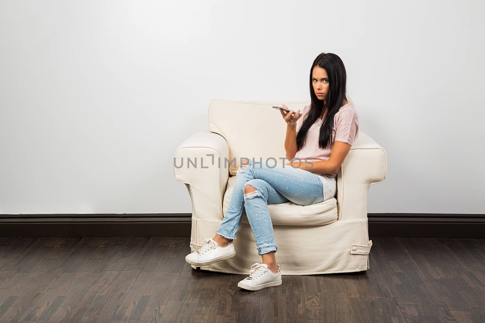 woman in her twenty sitting on a couch and talking on a smart phone