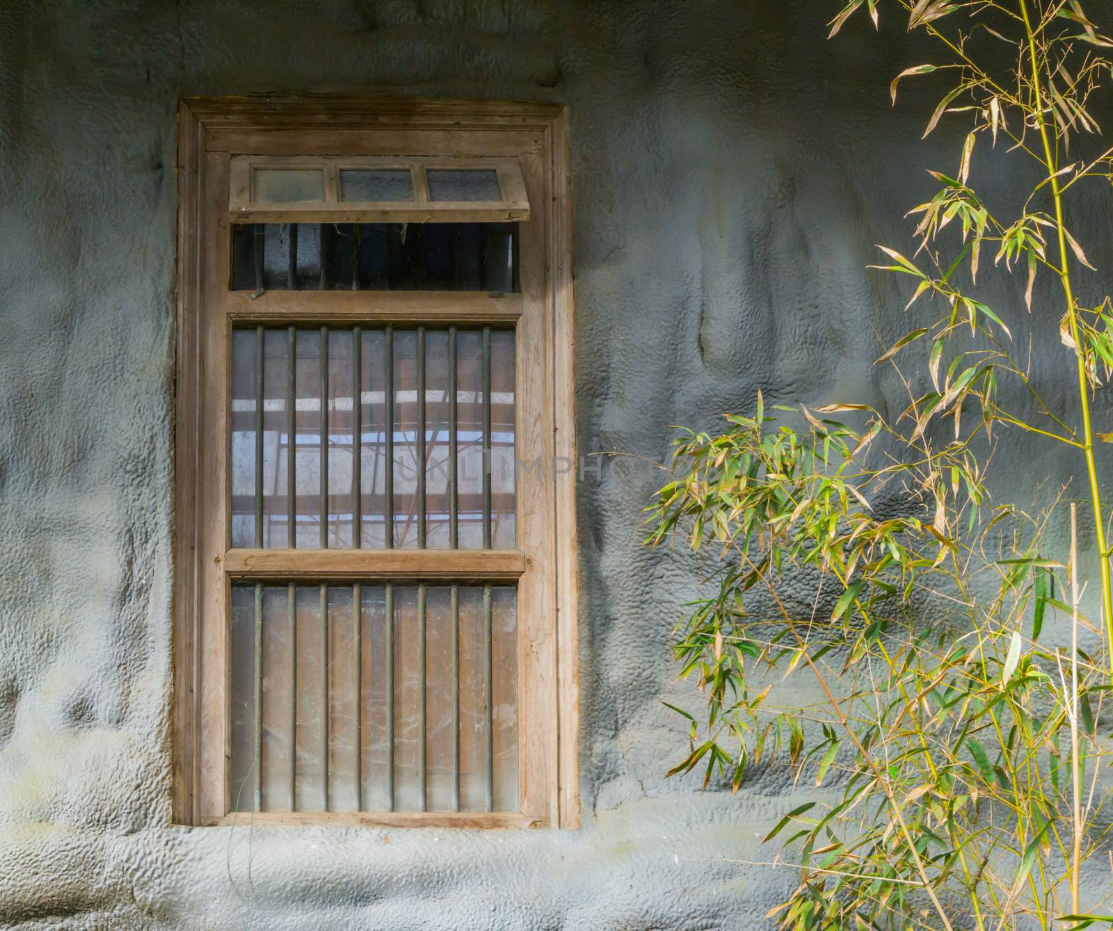 old dirty window framework with jail bars in a stone wall by charlottebleijenberg