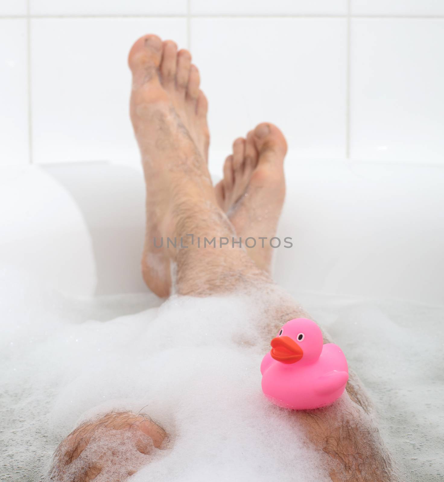 Men's feet in a bright white bathtub, selective focus on toes