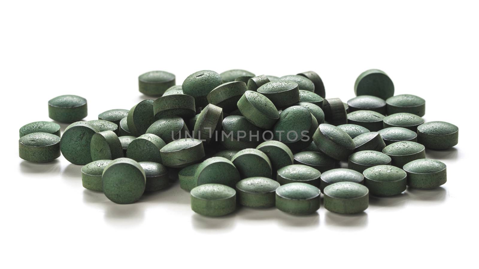 Close up of organic spirulina tablets over white background. 
