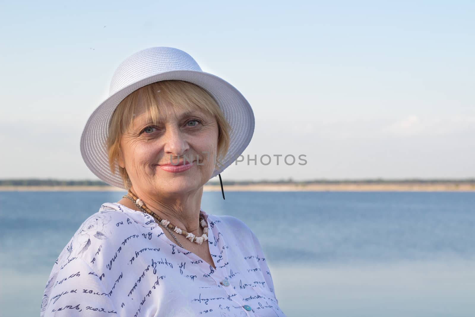 Happy smiling elederly retired lady woman rests in nature near lake river sea