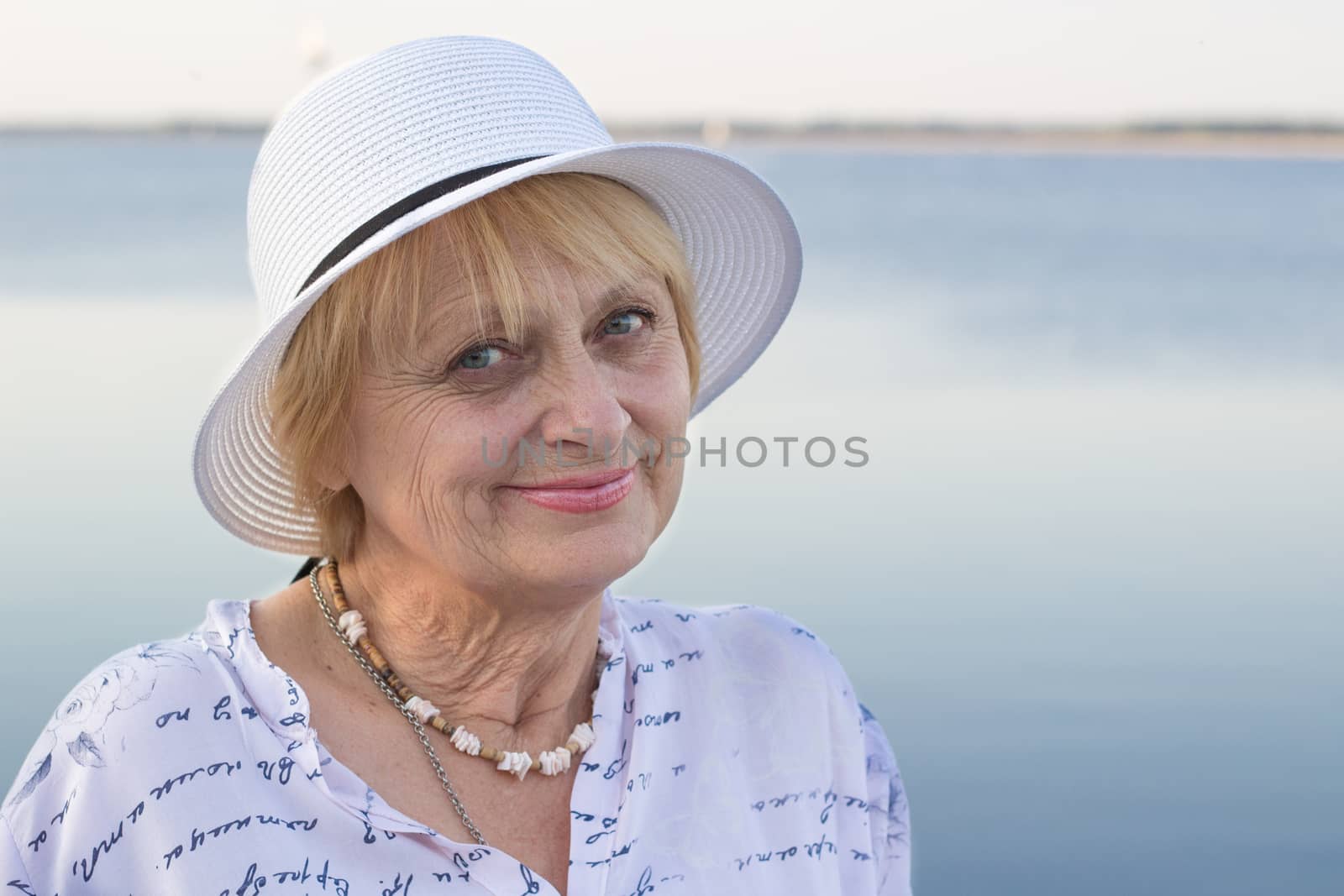 Happy retired lady rests in nature near sea by VeraVerano