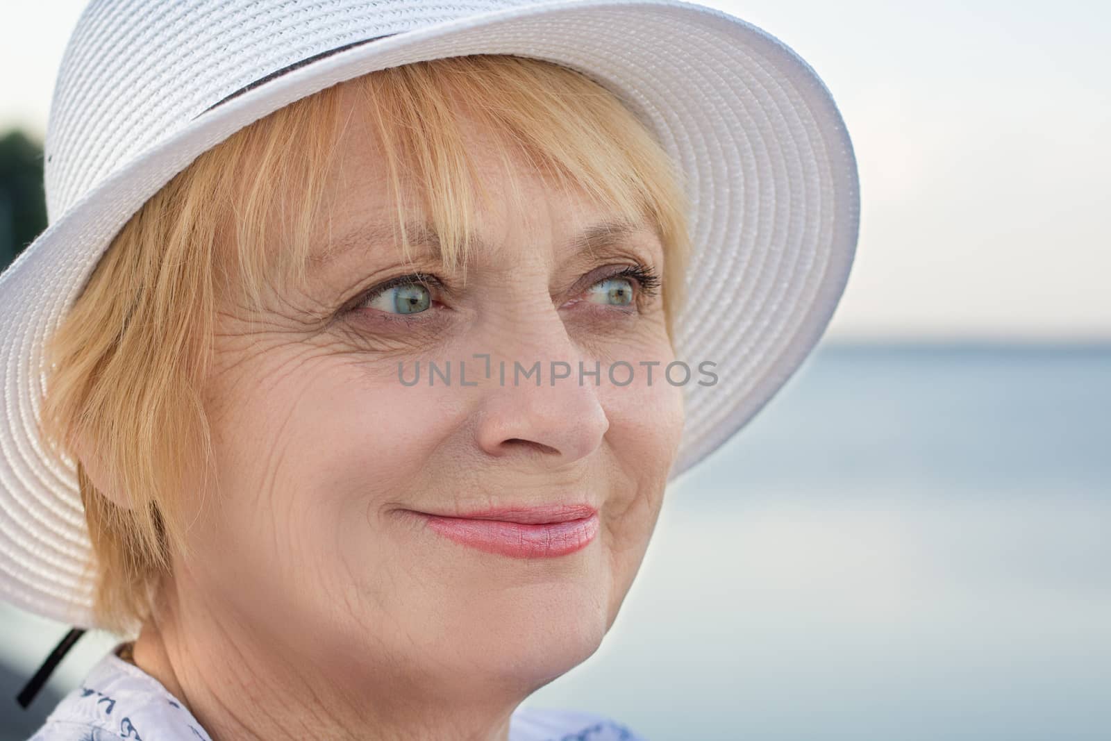 Happy smiling elederly retired lady woman rests in nature near lake river sea