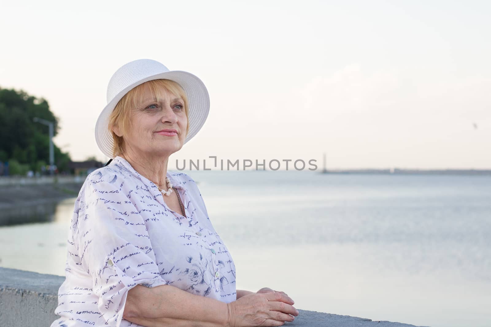 Happy smiling elederly retired lady woman rests in nature near lake river sea