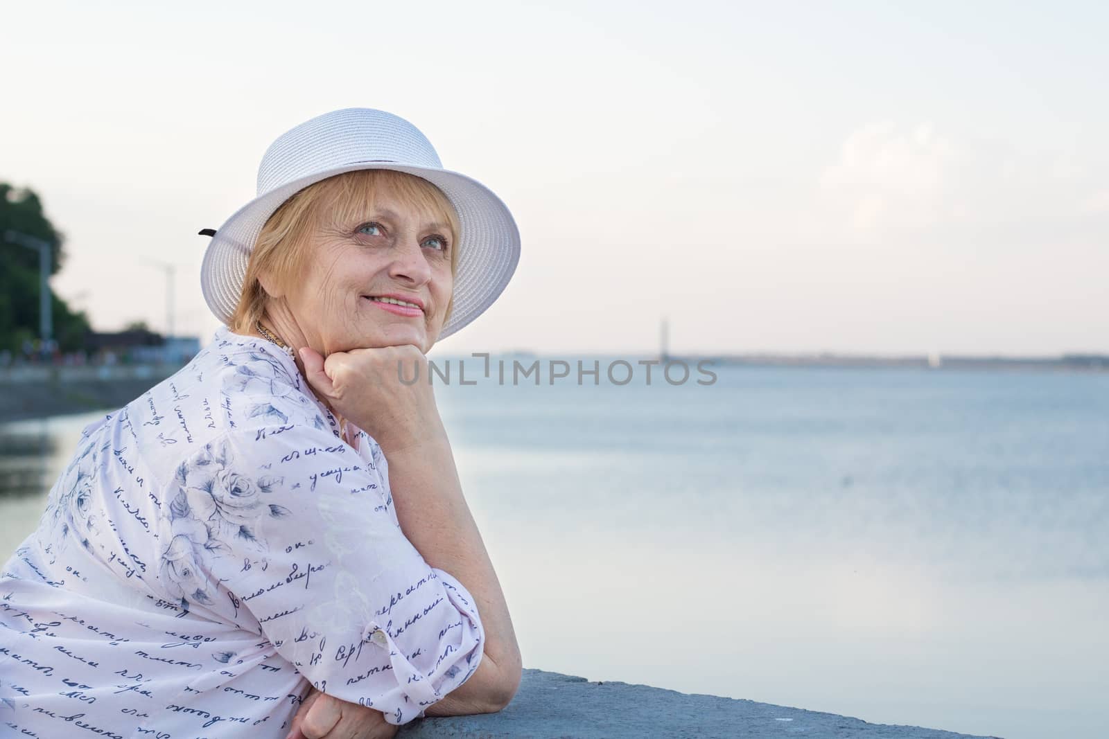 Happy smiling elderly lady woman rests in nature near lake river sea