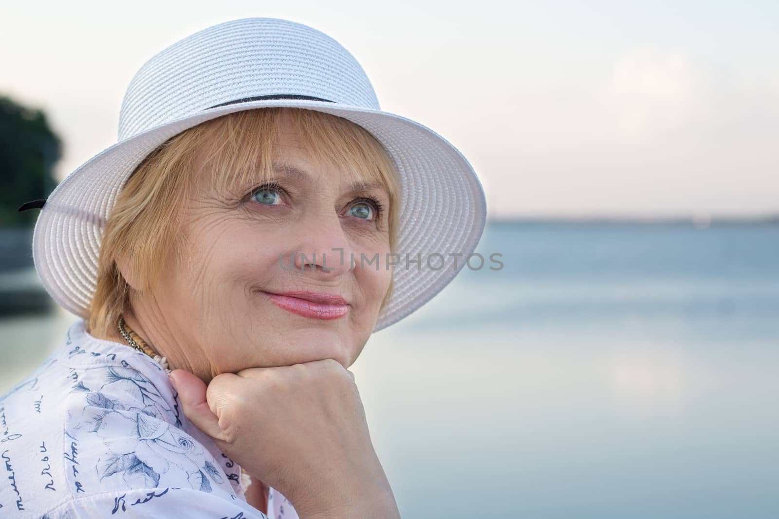Happy smiling elderly retired lady rests in nature near sea by VeraVerano
