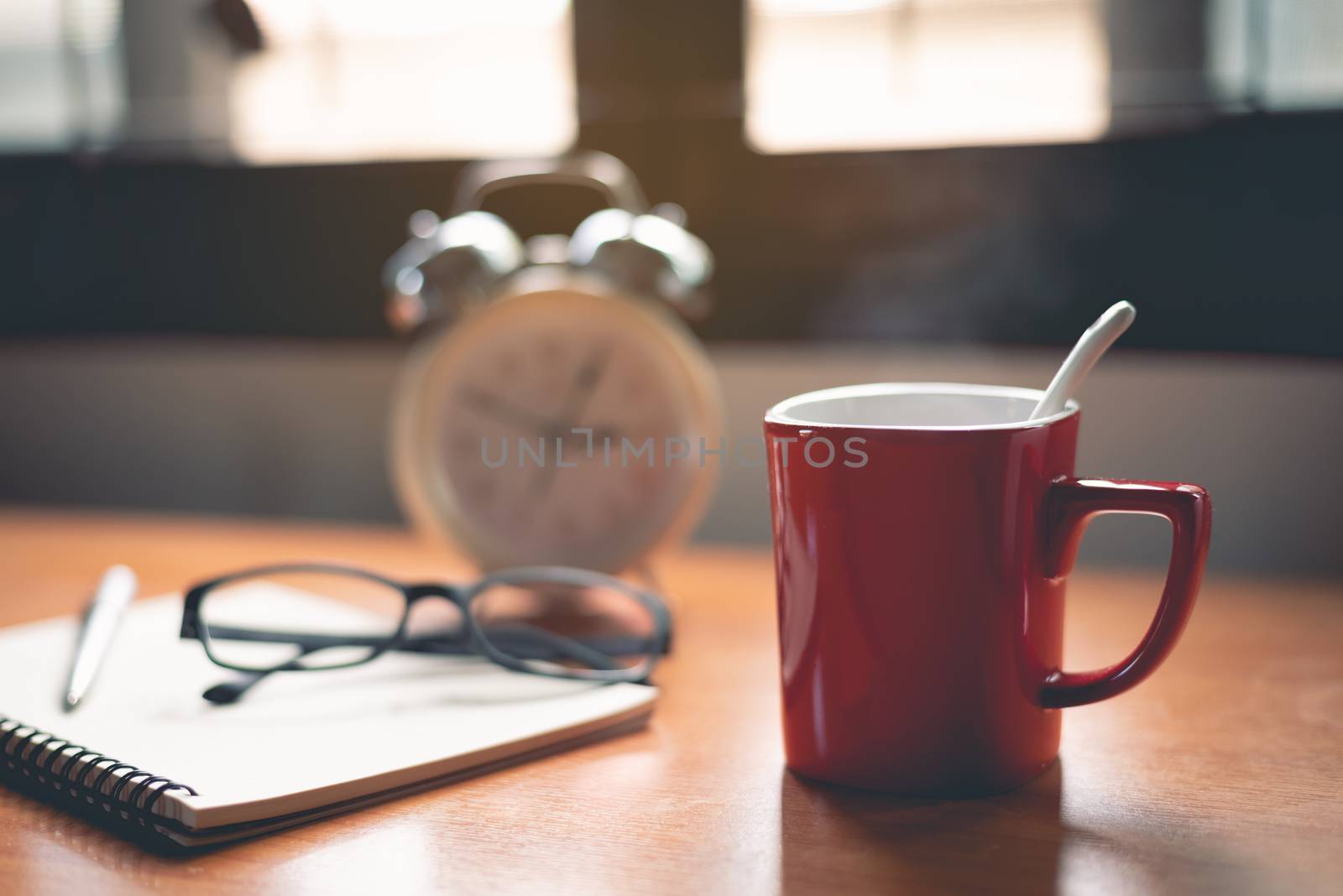 close up of red cup of coffee and clock on office table by Wmpix