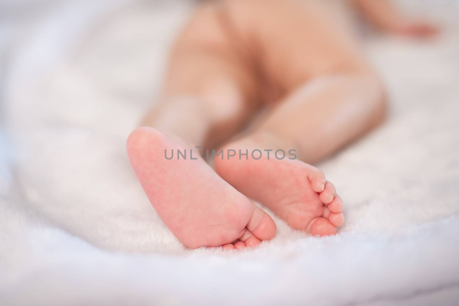 close up of feet baby on white bed by Wmpix